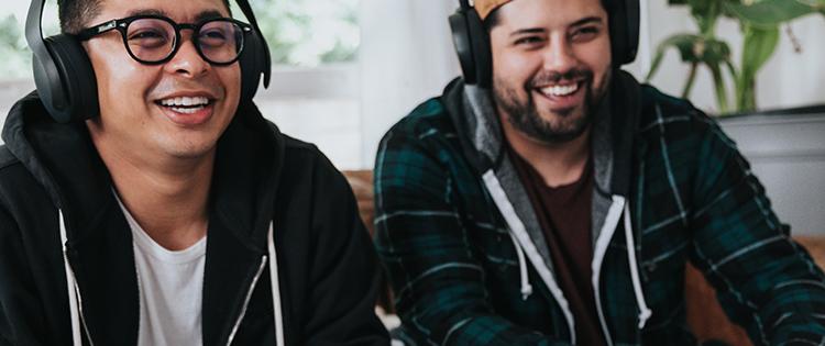 Two men with headphones on smiling.