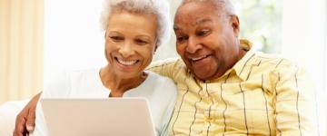 Senior african american couple using laptop happily